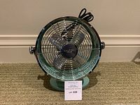 Front view showing aqua body, metal grill, and fan blades with Nautica Home logo at center.
