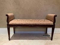 Front view of rolled arm bench showing full length, carved apron and damask upholstery.