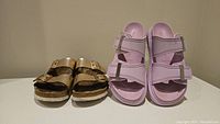 Two pairs of sandals placed side by side: rose gold metallic Birkenstocks and lavender Alexander McQueen sandals.