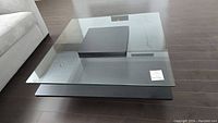 Top view of the square glass tabletop showing the polished glass edges and a note on the glass surface.
