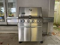 Front view of Weber Summit grill with closed lid, side stations and cabinet