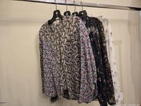 Five women's blouses hung on rack showing full arrangement and various patterns