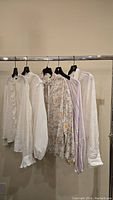 Rack view of five blouses on black hangers