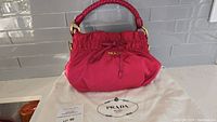 Front view of fuchsia pink Prada bag on dust cover