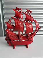 Front angle view of the red painted cast iron ship doorstop showing detailed sails and hull design.