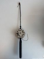 Full view of the antique stubby ice fishing rod with reel, showing the entire length and handle detail.