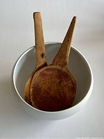 Top view of the white ceramic dome bowl holding two antique wooden dough spoons