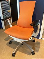 Front view of chair showing orange seat, back and black armrests