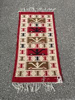 Full frontal image of Southwestern style rug lying flat on ground with visible fringes and geometric pattern