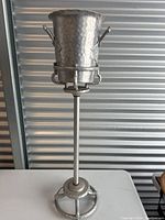Full view of the champagne bucket on the stand showing the tall vertical pole and circular base.