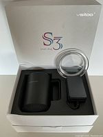 Open box showing black Vsitoo S3 smart mug, clear lid, and black power adapter in foam insert.