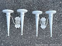 Top down view of the pair of sconces showing two candle posts each with round drip plates and white painted metal finish with minor wear.