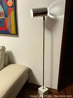 Full view of floor lamp showing slender rod, marble base, and chrome shade in upright position