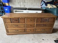 Front view of long oak dresser showing multiple drawers with metal pull handles and natural oak finish.