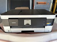 Front view showing Brother logo, touchscreen, power button, and printer model.