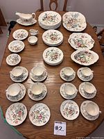 Full view of the 51-piece Copeland Spode Gainsborough dinnerware set arranged on a wooden table including plates, cups, saucers, and a gravy boat.