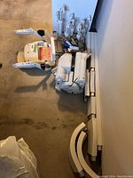 Photo showing the stairlift seat with armrests and controls next to multiple straight and curved rail sections and mechanical parts laid out on a garage floor.