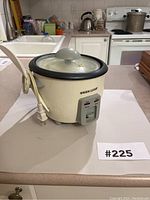 White Black & Decker rice cooker with power cord and glass lid on countertop.