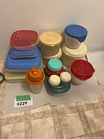 Top view of assorted food storage containers arranged on the floor showing various shapes and colors including red, blue, beige, and clear.