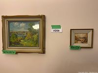 Both framed paintings hung on wall with green size labels and lot tag between them
