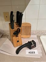 Full view of wooden knife block holding six knives and scissors, with knife sharpener placed in front.