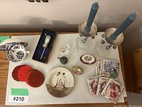 Overview of Limoges porcelain, vintage bar accessories including bottle stopper, crocheted coasters, decorative candle holders with blue candles, trinket boxes, small plate and floral coasters.