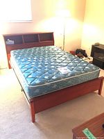 Full view of bed frame with mattress, showing wood finish and open shelves in headboard.