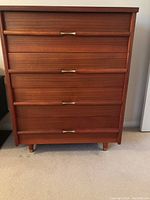 Front-facing view of the four-drawer teak highboy showing overall design and finish.
