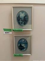 Two framed oval needlepoint landscape artworks stacked vertically on a wall.