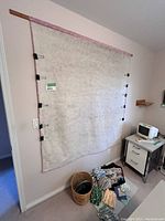 Quilting design wall with fabric covering and binder clips mounted on wall, with adjacent furniture and craft supplies visible.