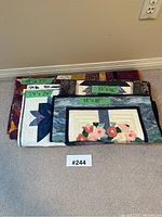 Five quilts stacked with size labels showing dimensions (49x77, 24x24, 18x18, 17x46, 17x7) and various patchwork patterns visible