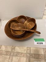 Photo showing the stacked large serving bowl with six smaller eating bowls inside and a wooden serving spoon on top, highlighting the wood grain and overall condition.