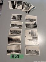 Photo of 14 black and white WW1 era photo print copies arranged on a table with a green label #50.