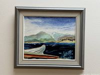 Framed oil painting on board depicting a coastal landscape with mountains and water, signed by Sabine Taylor.