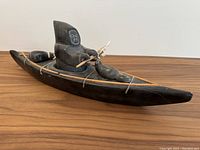 Front and side view of soapstone kayak carving showing hunter, seals, harpoon and oars.