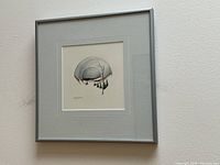 Framed and matted watercolour and ink artwork by Leola Smith hung on wall.