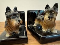 Close-up front view showing detailed faces of two ceramic Scottie dog bookends in black and tan.