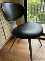 Front view of the chair showing black leather seat and bent wood backrest with metal legs.