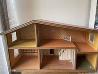 Front and side view of the doll house showing multiple rooms, stairway, and varied interior wallpaper patterns.