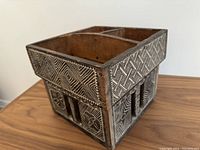 Angle view of vintage wooden betel nut preparation box showing intricate geometric and floral carvings highlighted with powdered lime on exterior sides.