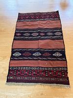 Full view of the vintage rectangular woven wool kilim rug laid on a wooden floor showing all pattern bands and condition.