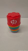 Close-up photo of the top piece of the stacking toys showing number 10 in white on red plastic with flower shape