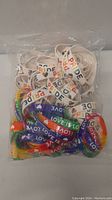 Photo of bag containing white PRIDE bracelets and multi-colored LOVE IS LOVE bracelets showing the variety and quantity of wristbands.