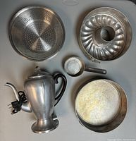 Electric coffee percolator, springform pans, small saucepan, colander/steamer, bundt pan displayed on table