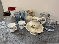Full lot view showing all glassware, canisters, mugs, ceramic pitcher, and wash bowl set