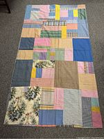 Full view of patchwork quilt topper laid flat, showing various fabric patterns and colors in rectangular and square shapes.