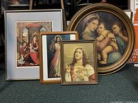 Five religious framed artworks arranged together. Four are rectangular, one is round with gold frame.