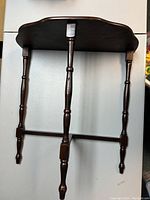 Front and side angle view of small wooden console end table showing turned legs and scalloped edge top.