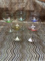 Four Spectrum hand blown balloon goblets with different colored bases on a patterned surface, visible front view