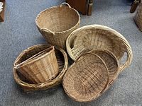 Five wicker baskets arranged grouped on a carpet. Various shapes and sizes visible.